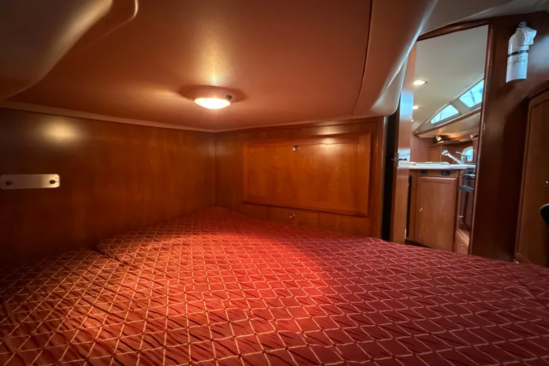 Slide: The Image of Cozy cabin interior of 2010 Hunter 36 sailboat with wood paneling and red bedding. - 15