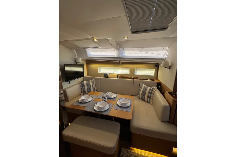 Slide: The Image of Interior of 2022 Jeanneau Sun Odyssey 440 yacht, featuring a cozy dining area with elegant table settings. - 2