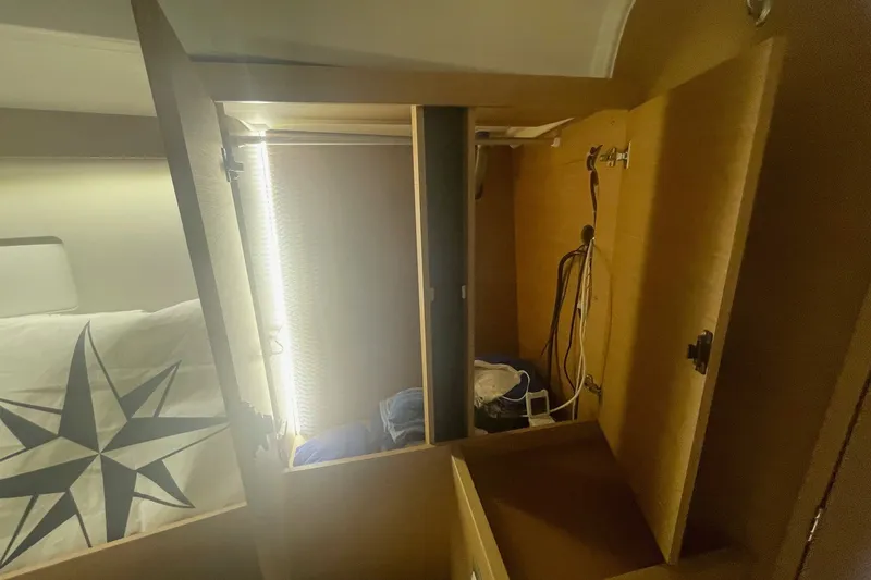 Slide: The Image of Interior of 2022 Jeanneau Sun Odyssey 440 showing open wooden cabinets and nautical bedding. - 9