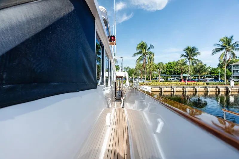 Slide: The Image of 2005 Grand Banks 72 Aleutian RP yacht docked by palm trees and waterfront. - 125