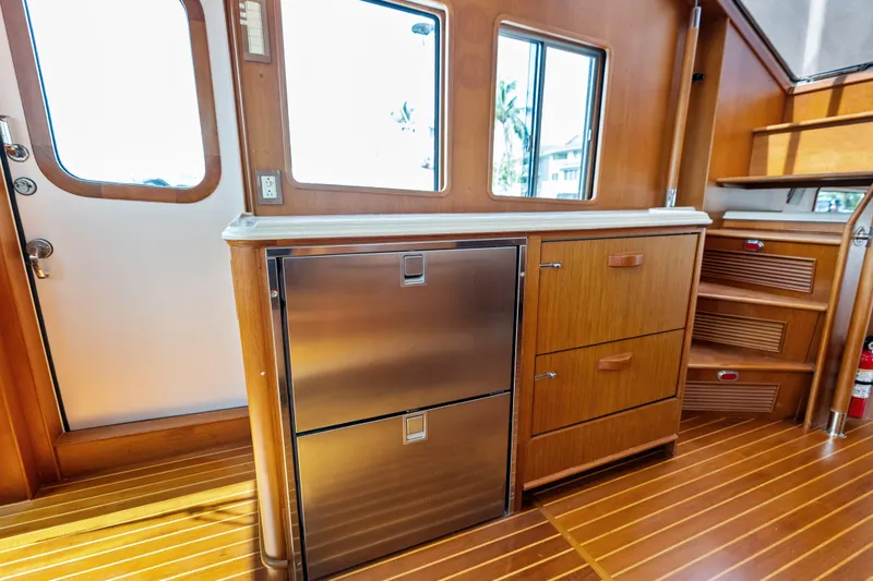 Slide: The Image of Interior of 2005 Grand Banks 72 Aleutian RP yacht with wooden cabinetry and stainless steel fridge. - 80