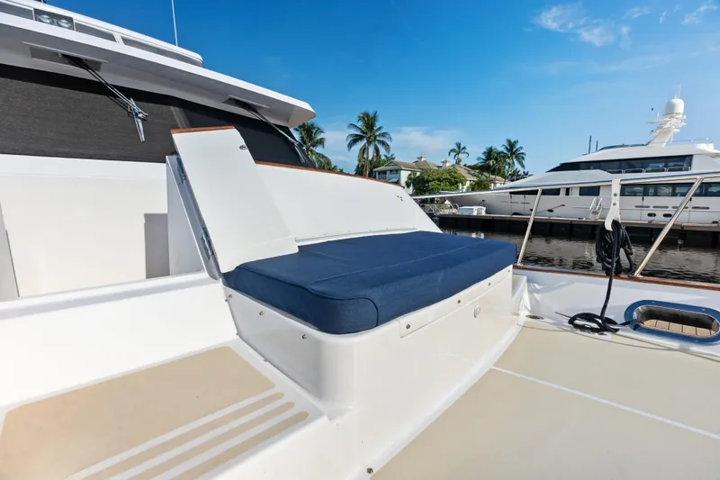 Slide: The Image of 2005 Grand Banks 72 Aleutian RP yacht deck with blue cushioned seating, docked near palm trees. - 122