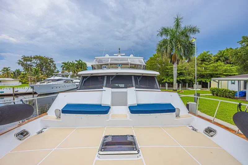 Slide: The Image of 2005 Grand Banks 72 Aleutian RP yacht docked, featuring spacious deck and lush surroundings. - 17