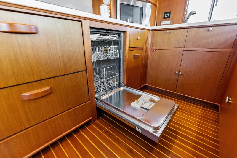 Slide: The Image of Open dishwasher in the wooden kitchen of a 2005 Grand Banks 72 Aleutian RP yacht. - 77