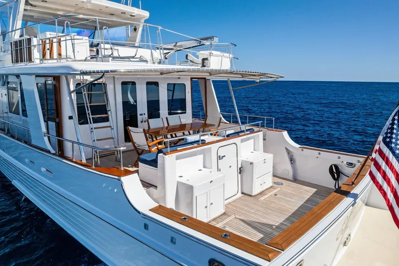 Slide: The Image of 2005 Grand Banks 72 Aleutian RP yacht on open sea, featuring spacious deck and American flag. - 37
