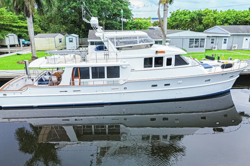 The Image of 2005 Grand Banks 72 Aleutian RP yacht docked by lush greenery and waterfront homes. - 0