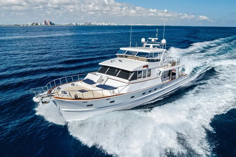 Slide: The Image of 2005 Grand Banks 72 Aleutian RP yacht cruising on open ocean with city skyline backdrop. - 195