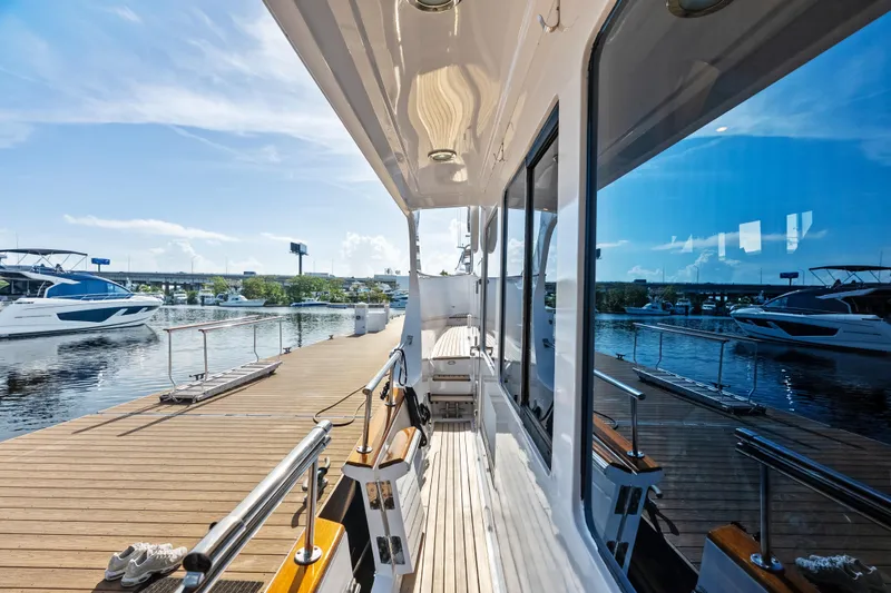 Slide: The Image of 2005 Grand Banks 72 Aleutian RP yacht docked, reflecting water and sky, with nearby boats. - 115