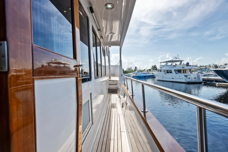 Slide: The Image of 2005 Grand Banks 72 Aleutian RP yacht docked, showcasing sleek wooden deck and marina view. - 113