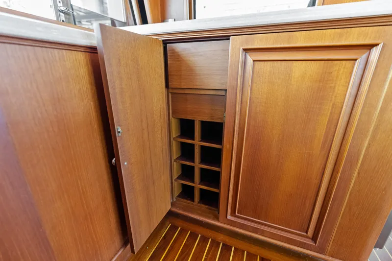 Slide: The Image of Wooden cabinet with open door revealing storage shelves on 2005 Grand Banks 72 Aleutian RP yacht. - 76
