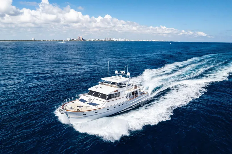Slide: The Image of 2005 Grand Banks 72 Aleutian RP yacht cruising on open ocean with city skyline in background. - 197
