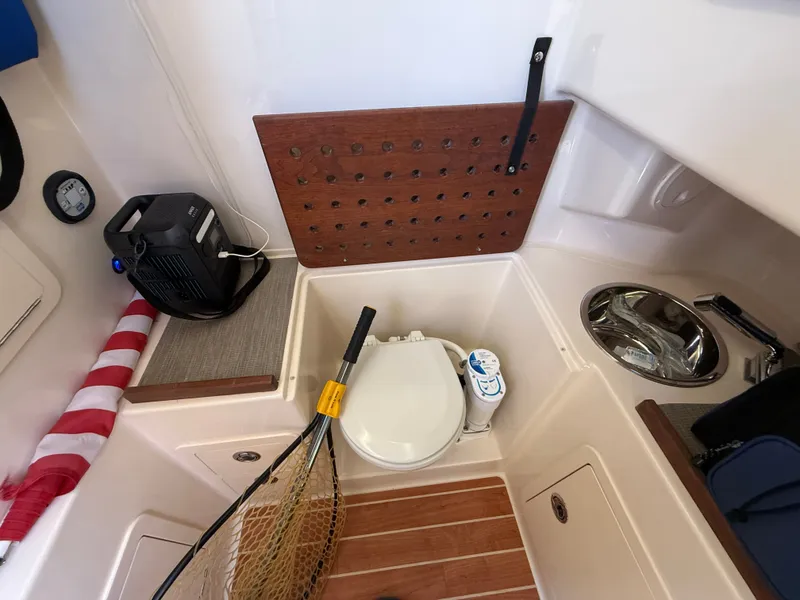 Slide: The Image of The image shows the interior of a Grady-White Canyon 306 boat with a toilet and fishing gear. - 37