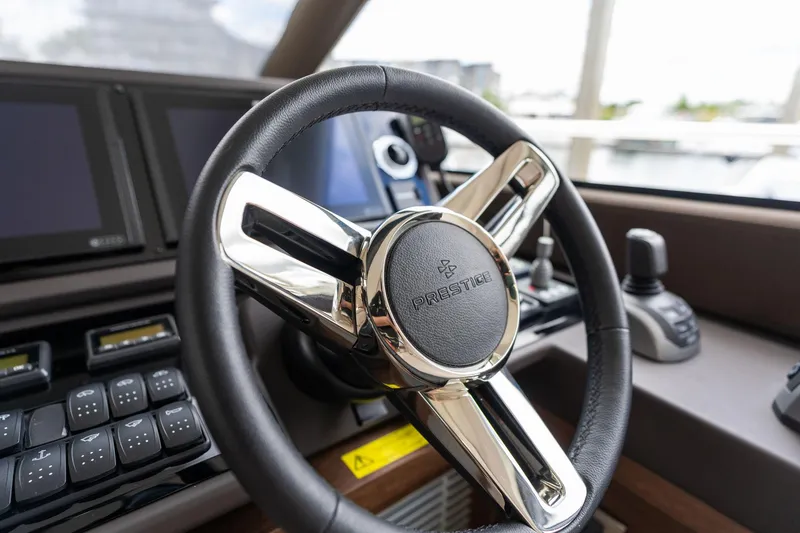 Slide: The Image of Steering wheel of a 2022 Prestige 520 yacht, featuring modern controls and displays. - 33