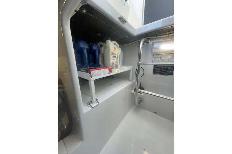 Slide: The Image of Storage compartment in a 2009 L&H 33 Walkaround boat with oil containers and supplies. - 22