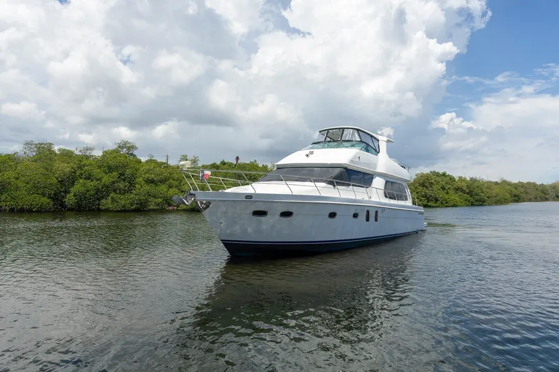 Slide: The Image of 2007 Carver 56 Voyager SE yacht cruising on a serene waterway under a cloudy sky. - 2
