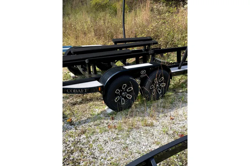 Slide: The Image of Trailer for 2022 Cobalt R8 Surf boat on gravel path, surrounded by grass. - 77