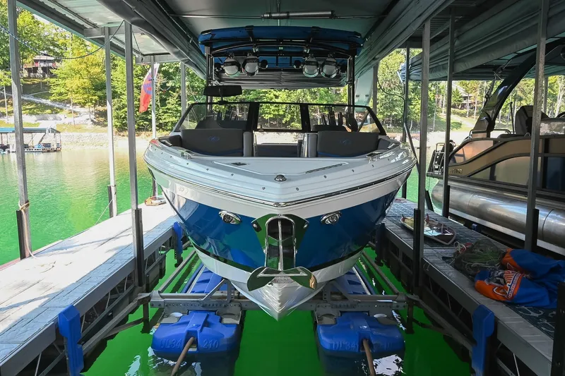 Slide: The Image of 2022 Cobalt R8 Surf boat docked in a marina with vibrant green water. - 1