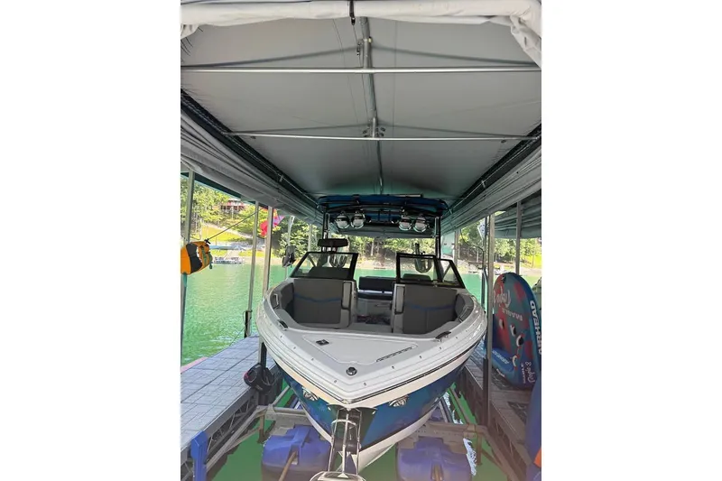 The Image of 2022 Cobalt R8 Surf boat docked under a canopy on a serene lake. - 1