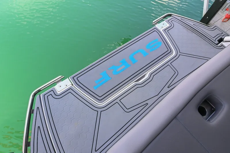 Slide: The Image of 2022 Cobalt R8 Surf boat swim platform with "SURF" logo, near green water. - 7