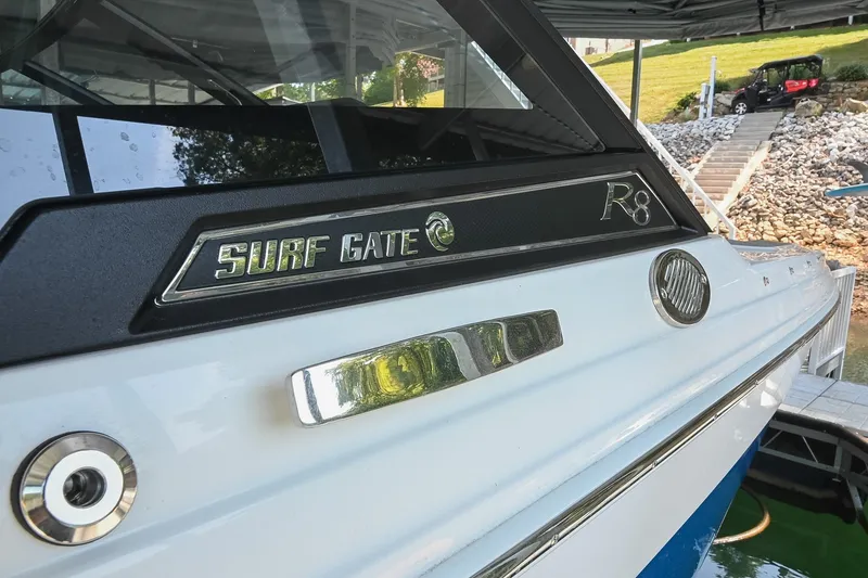 Slide: The Image of 2022 Cobalt R8 Surf boat with Surf Gate feature, docked near a rocky shoreline. - 5