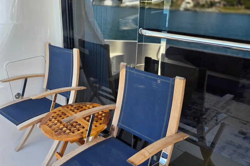 Slide: The Image of Outdoor seating on 2005 Sea Ray 550 Sedan Bridge yacht, featuring blue chairs and wooden table. - 59