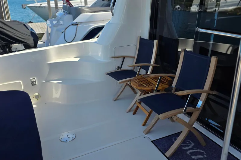 Slide: The Image of 2005 Sea Ray 550 Sedan Bridge yacht deck with chairs and table, docked at marina. - 61