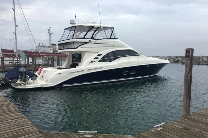 The Image of 2005 Sea Ray 550 Sedan Bridge yacht docked at a marina, overcast sky. - 0