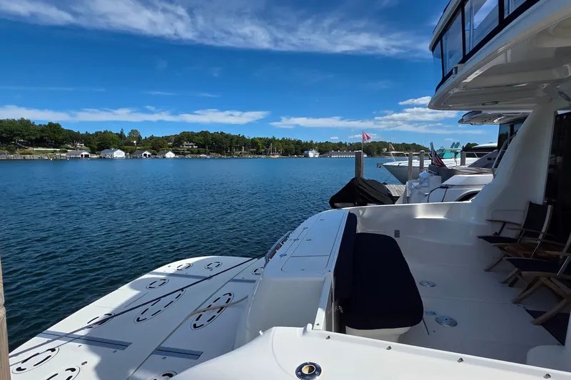 Slide: The Image of 2005 Sea Ray 550 Sedan Bridge yacht docked on a serene lake under a clear blue sky. - 67