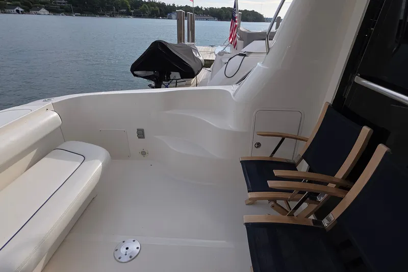 Slide: The Image of 2005 Sea Ray 550 Sedan Bridge yacht deck with seating, overlooking serene water. - 60