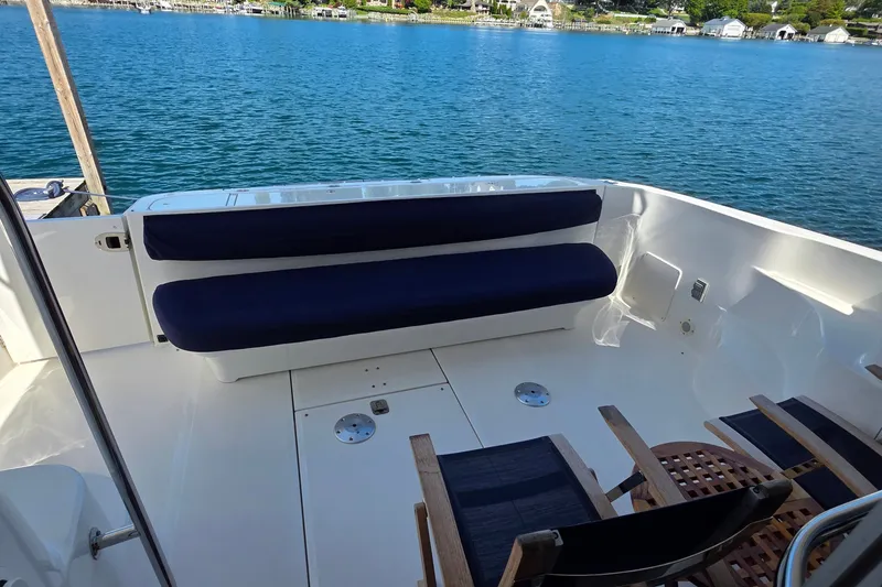 Slide: The Image of 2005 Sea Ray 550 Sedan Bridge yacht deck with seating, overlooking serene waterfront. - 64