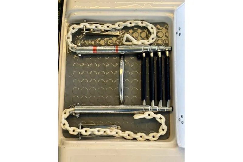 Slide: The Image of Boat equipment storage on a 1992 Tiara 270 Sport, featuring chains and metal rods. - 21