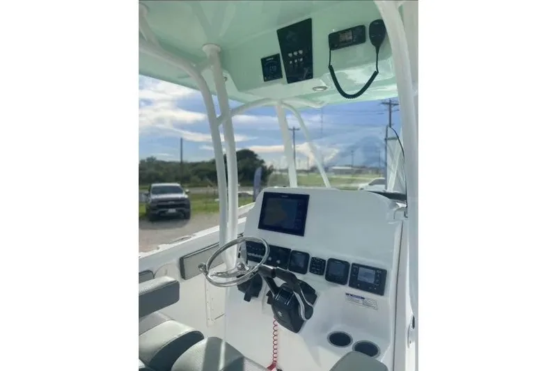 Slide: The Image of 2021 Aquasport 2500 Center Console boat dashboard with steering wheel and electronic controls. - 23