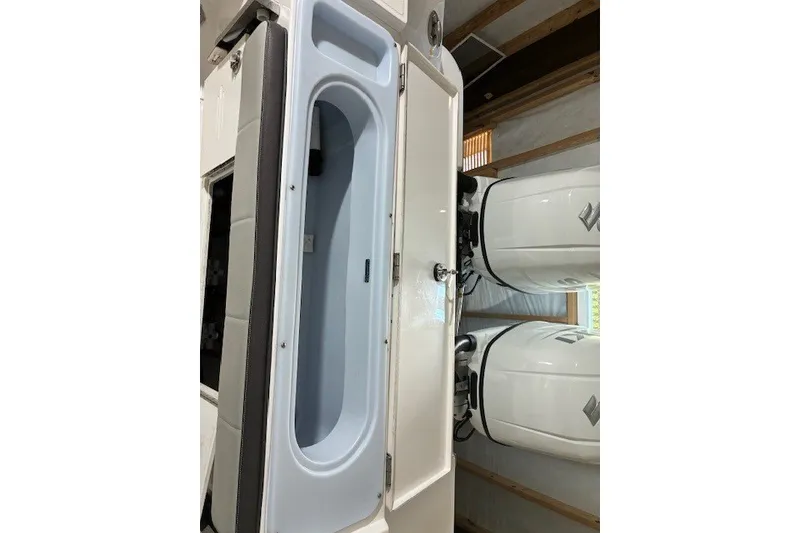 Slide: The Image of 2021 Aquasport 2500 Center Console with open storage compartment and dual outboard engines. - 27