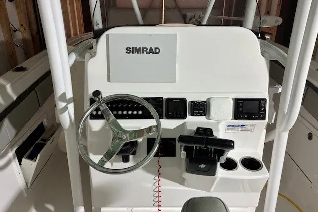 Slide: The Image of 2021 Aquasport 2500 Center Console boat dashboard with Simrad display and steering wheel. - 28