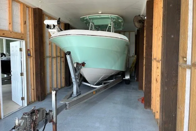 Slide: The Image of 2021 Aquasport 2500 Center Console boat stored in a wooden garage on a trailer. - 2