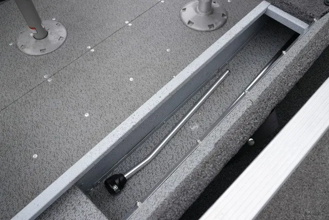 Slide: The Image of The image shows the interior of a 2023 Lund 1600 Fury SS boat with gray carpeting and storage compartment. - 13