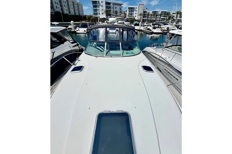 Slide: The Image of 2006 Rinker 320 Express Cruiser docked at a marina with modern buildings in the background. - 14
