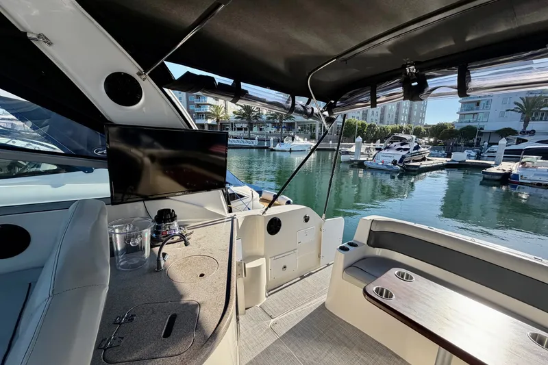 Slide: The Image of 2006 Rinker 320 Express Cruiser interior with marina view, featuring seating and entertainment area. - 29