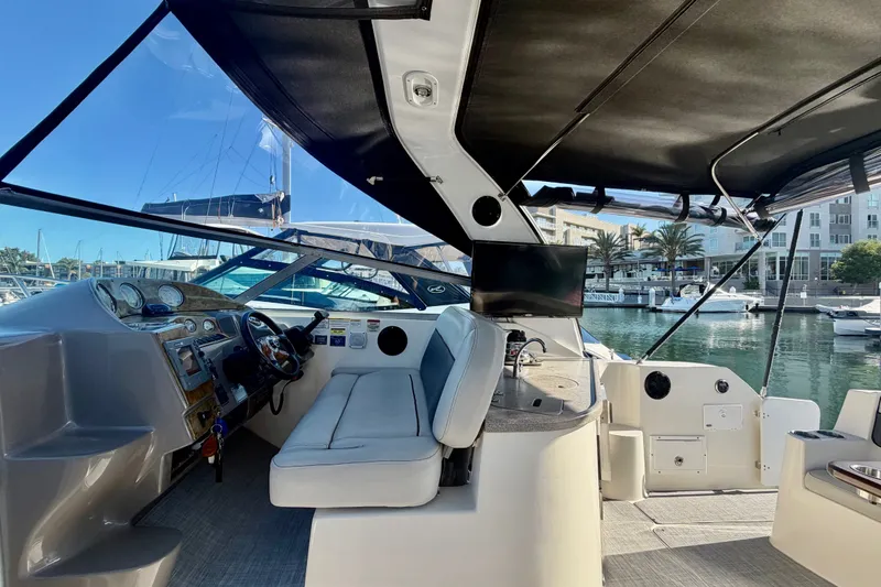 Slide: The Image of 2006 Rinker 320 Express Cruiser interior with helm, seating, and marina view. - 26