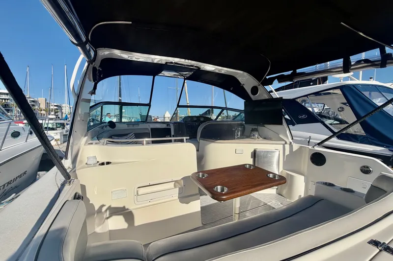 Slide: The Image of 2006 Rinker 320 Express Cruiser interior with seating and table, docked at marina. - 17