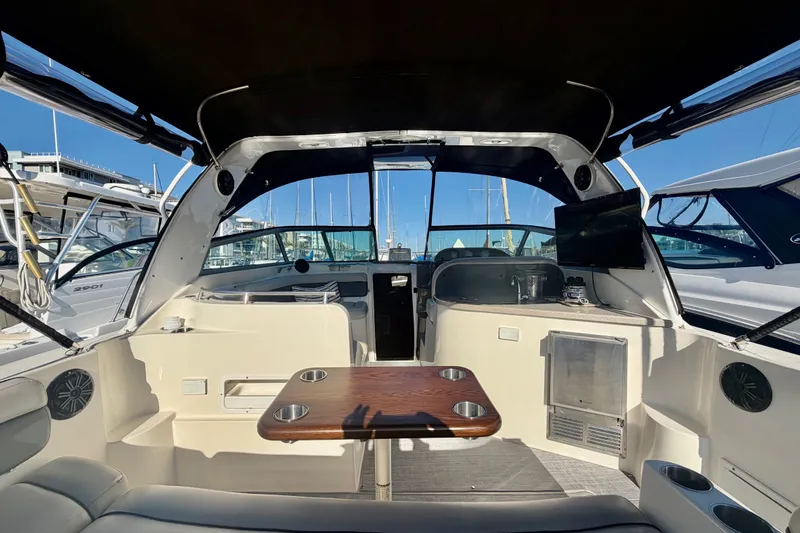 Slide: The Image of 2006 Rinker 320 Express Cruiser interior with seating, table, and marina view. - 18