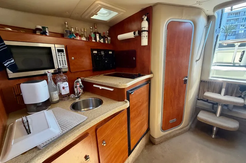 Slide: The Image of 2006 Rinker 320 Express Cruiser interior kitchen with microwave, sink, and wooden cabinetry. - 51