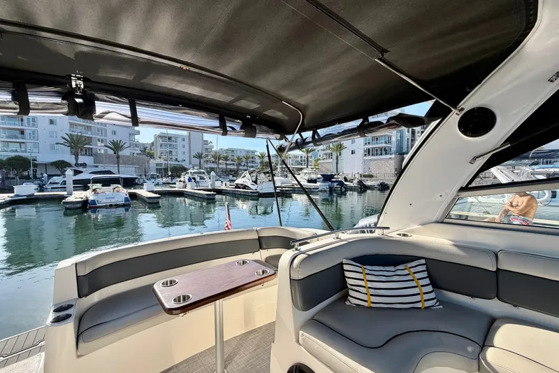Slide: The Image of 2006 Rinker 320 Express Cruiser interior with marina view, featuring comfortable seating and a table. - 28