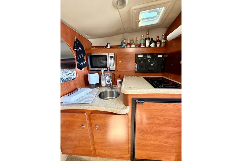 Slide: The Image of 2006 Rinker 320 Express Cruiser kitchen with microwave, sink, and countertop appliances. - 49