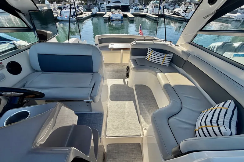 Slide: The Image of 2006 Rinker 320 Express Cruiser interior with plush seating and striped cushions at marina. - 25