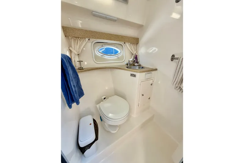 Slide: The Image of 2006 Rinker 320 Express Cruiser bathroom with toilet, sink, and porthole window. - 53