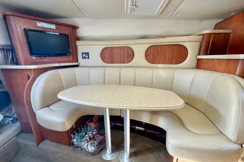 Slide: The Image of 2006 Rinker 320 Express Cruiser interior with curved seating and table, featuring a mounted TV. - 47