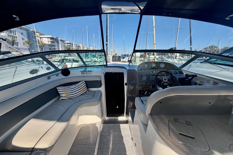 Slide: The Image of 2006 Rinker 320 Express Cruiser interior with helm, seating, and marina view. - 20