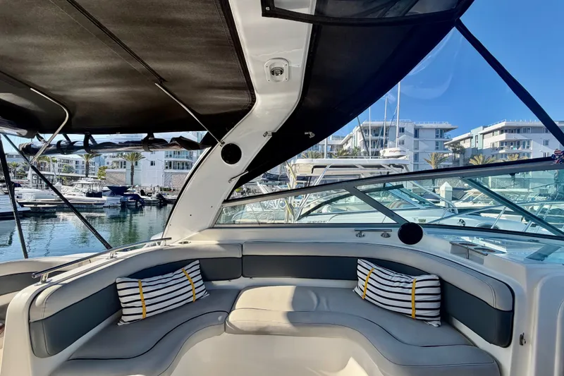 Slide: The Image of 2006 Rinker 320 Express Cruiser interior with striped cushions, docked at a marina. - 27