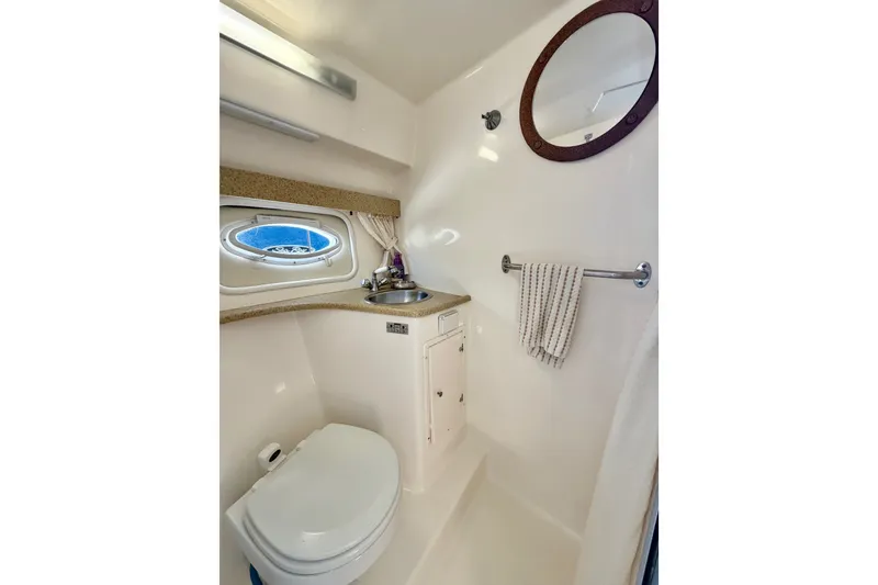 Slide: The Image of 2006 Rinker 320 Express Cruiser bathroom with toilet, sink, and porthole window. - 52